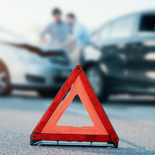 Red warning triangle in front of a car accident.