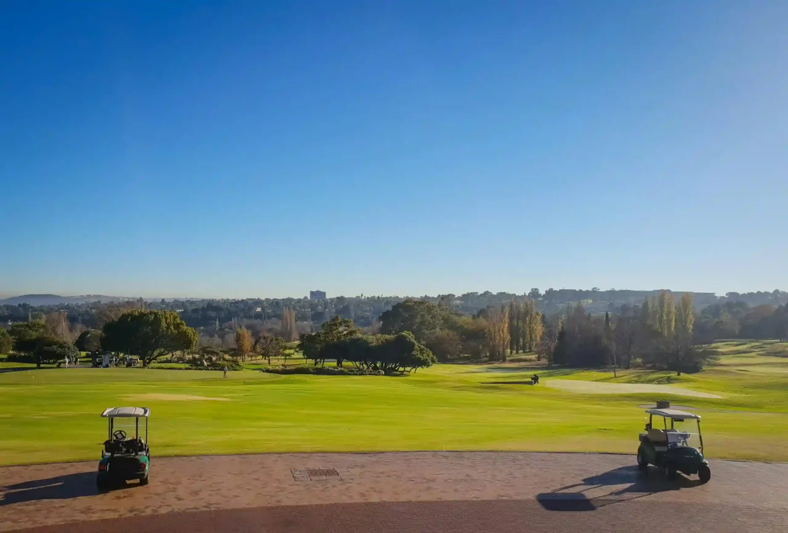 Two buggies at a golf course on a sunny day