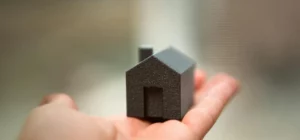 Mini house sculpture held in hand representing unoccupied building insurance
