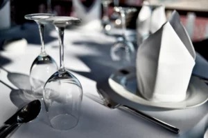 Restaurant table setting with wine glasses, cutlery and folded napkins